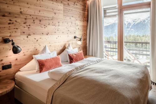 a bedroom with a large bed with a large window at NIDUM - Casual Luxury Hotel in Seefeld in Tirol