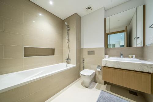 a bathroom with a tub and a toilet and a sink at Primestay - Creekside 18 Creek Harbour in Dubai