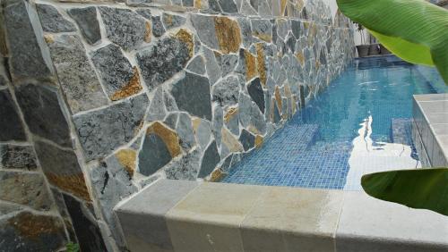 a swimming pool with a stone wall and a blue tiled floor at PENTHOUSE STOLIV Villa located 5 meters from the sea SPA-Pool Exclusive Terrace,Private Jetty Sunbeds, Pebble Beach, Secluded location Total area 375m2 at your disposal in Kotor