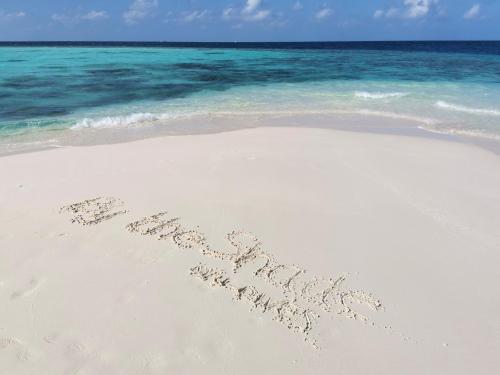 a word written in the sand on a beach at By the shade Maldives in Hangnaameedhoo