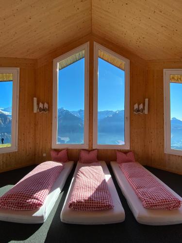 three beds in a room with three windows at Berggasthaus First - Only Accessible by Cable Car in Grindelwald