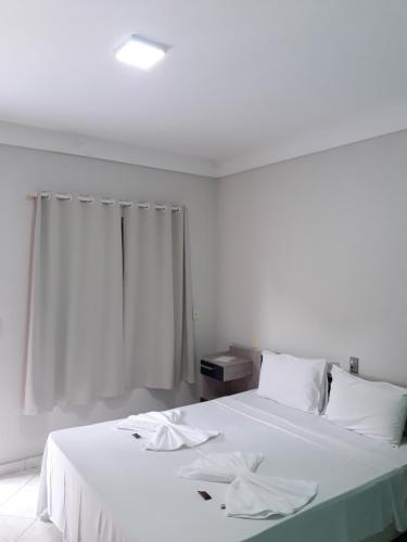 a bedroom with two beds with white sheets and a window at Pousada Askalon in Itaúnas