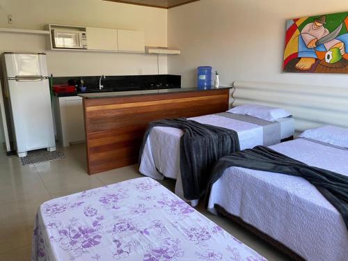 a room with three beds and a kitchen at Flat no Caribe in Maragogi