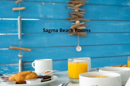 a table with breakfast foods and a glass of orange juice at Sagma Beach Rooms in Perissa