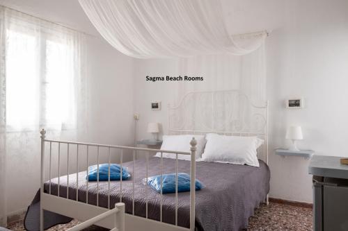 a bedroom with a bed with blue pillows on it at Sagma Beach Rooms in Perissa