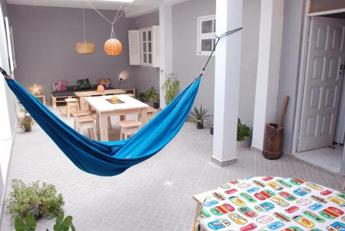 a blue hammock in a living room with a table at Cloud7 Beach Hostel in Tarrafal