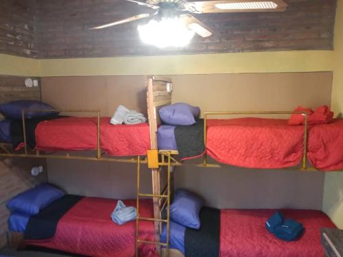 three bunk beds in a room with a ceiling at El Gringo Tito in La Falda
