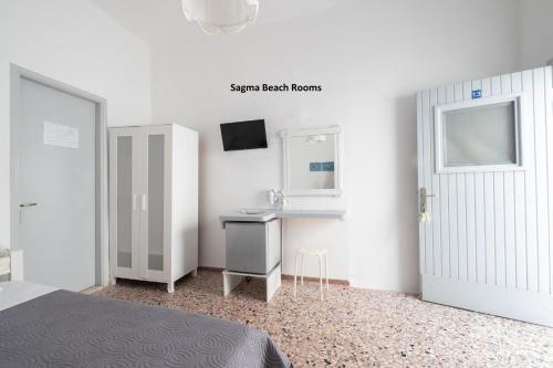 1 dormitorio con cama, lavabo y espejo en Sagma Beach Rooms en Perissa