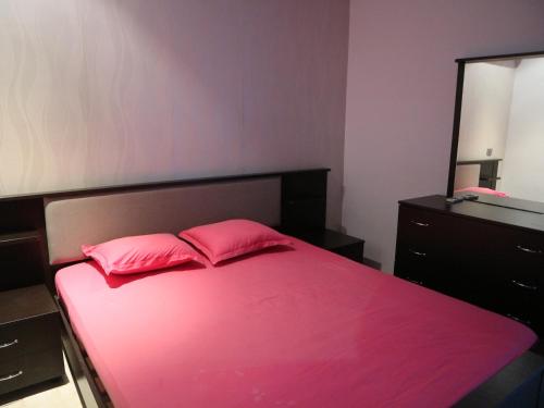 a bedroom with a bed with pink sheets and a mirror at Appartment Central Hammam Sousse plage in Sousse