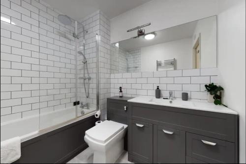 a bathroom with a toilet and a sink and a tub at Modern 2 bedroom flat with patio in Turnpike Lane in London