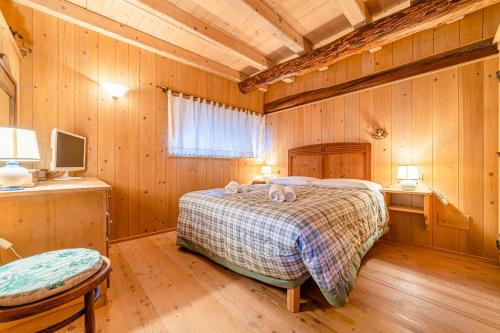 1 dormitorio con 1 cama en una habitación con paredes de madera en Chalet Sottoguda en Rocca Pietore