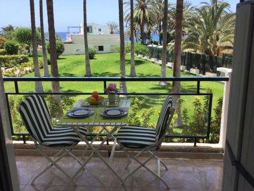 una mesa y sillas en un balcón con palmeras en Studio ocean coast Los Cristianos Comodoro en Los Cristianos