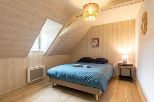 a bedroom with a blue bed in a attic at Le 32-GregIMMO-Appart'Hôtel in Montbéliard