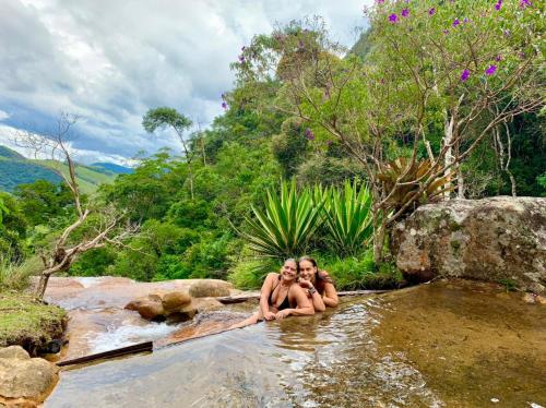 two women sitting in the water in a river at Chales Bamboo Jungle in Petrópolis