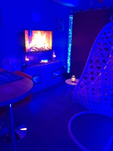 een blauwe kamer met een tv en een tafel en stoelen bij Lov'appart in Boulogne-sur-Mer