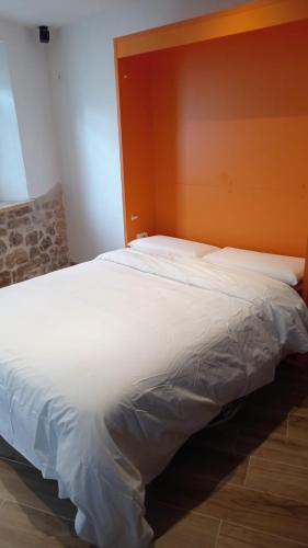 a bedroom with a large white bed with an orange headboard at El nido del Rusiñol in Cervera de Pisuerga