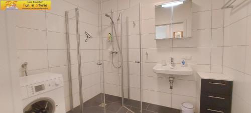 a bathroom with a shower and a sink and a washing machine at Apartment Bergzeit by FiS - Fun in Styria in Öblarn
