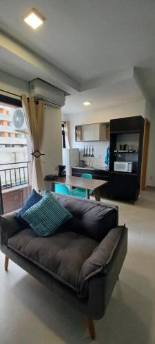 a leather couch in a living room with a kitchen at Vida Studios in Palhoça