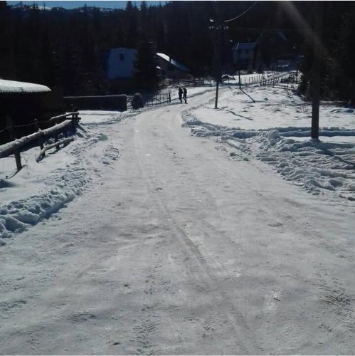 a road covered in snow with people walking down it at Markov konak in Jahorina