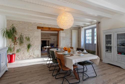 une salle à manger avec une table et des chaises blanches dans l'établissement La maison de Charlotte - chambres d'hôtes-Futuroscope, à Amberre