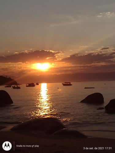 una puesta de sol sobre un cuerpo de agua con barcos en Pousada Mar de Araçatiba, en Praia de Araçatiba