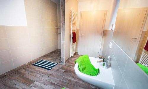 ein Badezimmer mit einem Waschbecken und einer Badewanne mit einem grünen Handtuch in der Unterkunft Das Dorfnest in Sankt Margarethen im Lungau