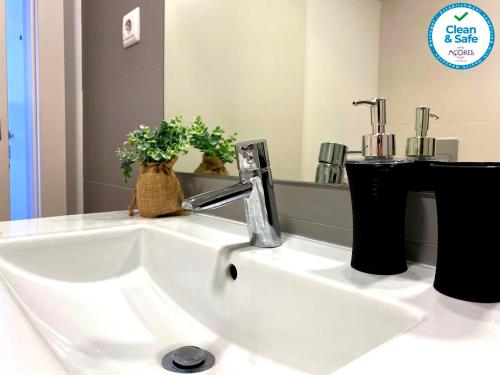 a white sink in a bathroom with a mirror at Karamba Azores AP central in Ponta Delgada