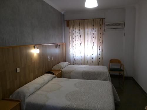 a hotel room with two beds and a window at Hostal Manolete in Lanjarón