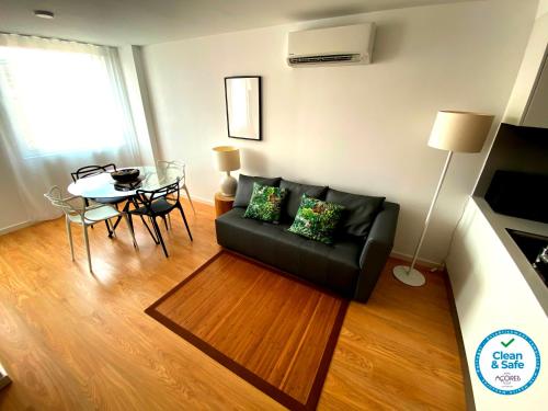 a living room with a black couch and a table at Karamba Azores AP central in Ponta Delgada