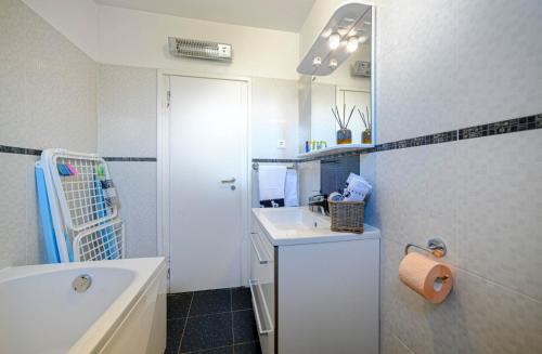 La salle de bains est pourvue d'un lavabo, d'une baignoire et d'un miroir. dans l'établissement Apartments Oto, à Žaborić