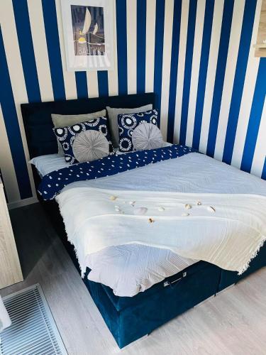 1 cama con pared de rayas azul y blanco en Apartament Marina, en Dziwnówek