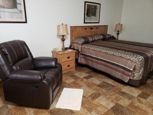a bedroom with a bed and a couch and a chair at Travelodge by Wyndham Deadwood in Deadwood