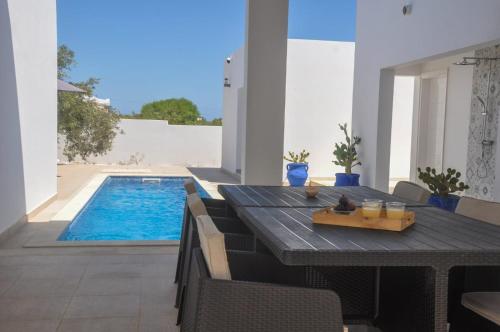 une table à manger avec des chaises et une piscine dans l'établissement Villa Salem Maison d'architecte toute équipée & piscine, à Arkou