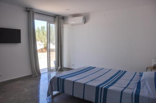 a bedroom with a bed and a sliding glass door at Villa Salem Maison d'architecte toute équipée & piscine in Arkou