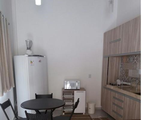 een keuken met een tafel en een witte koelkast bij Flat 259 localizado no Condomínio Solar Água in Pipa