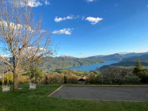 a view of a lake from a park with two benches at Belle maison Vue imprenable lac de Serre-Ponçon in Prunières