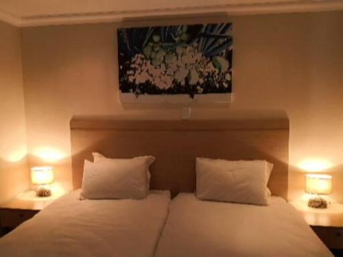 a bedroom with a bed with two pillows and two lamps at 17 on 13th in Edenvale