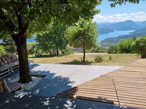 a wooden walkway with a bench and a view of a lake at Belle maison Vue imprenable lac de Serre-Ponçon in Prunières