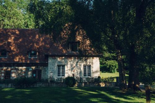 a stone house with a tree in front of it at Le prieuré des fontaines in Les Préaux