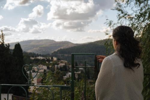 a woman standing on a balcony looking at a valley at Khan Ein Karem Boutique Hotel in Jerusalem