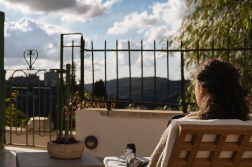 a woman sitting in a chair looking out at the view at Khan Ein Karem Boutique Hotel in Jerusalem