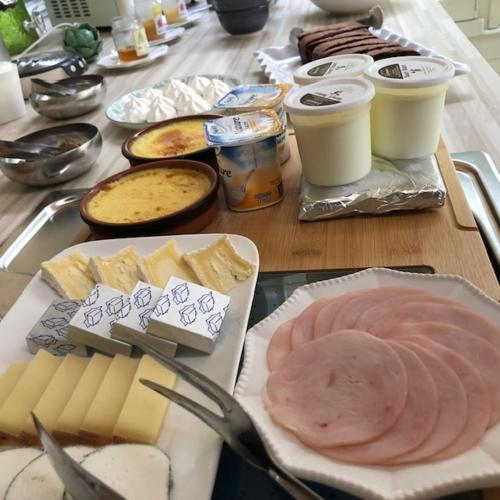 a table with cheese and ham and other foods on it at Le prieuré des fontaines in Les Préaux