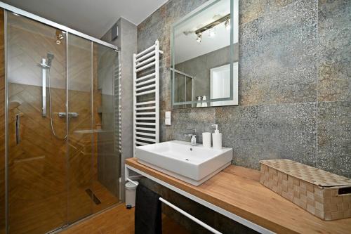 ein Bad mit einem Waschbecken und einer Dusche in der Unterkunft Szczyrk Apartament Niebo - sauna 6 osób in Szczyrk