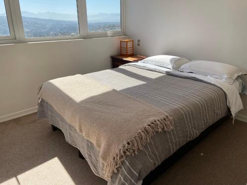 una camera da letto con un grande letto con due finestre di Departamento con increíble vista a Viña del Mar a Viña del Mar