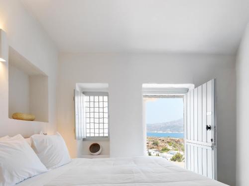 a white bedroom with a view of the ocean at The Windmill Kimolos in Kimolos