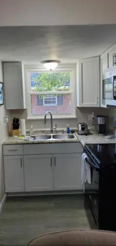 cocina con armarios blancos, fregadero y ventana en A great newly renovated place to stay in Franklin, en Franklin