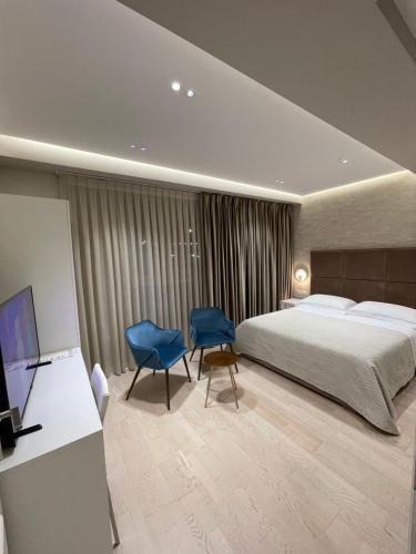 a hotel room with a bed and two blue chairs at Hotel Oresti Center in Tirana