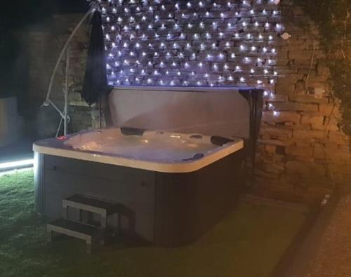 a bath tub with lights on a brick wall at Honeybee Cottage, with a log fire & a hot tub. in Bradford