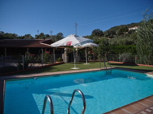 a swimming pool in a yard with an umbrella at VILLA BASILIO in Constantina