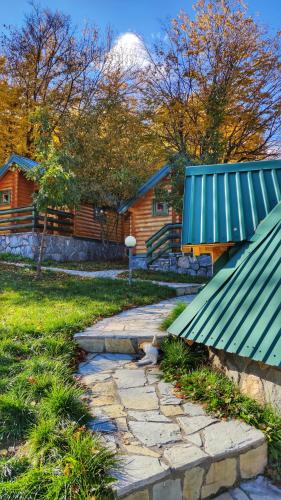 a stone path leading to a cabin with a snow covered mountain at KOZAK Apartments & Restaurant in Mojkovac